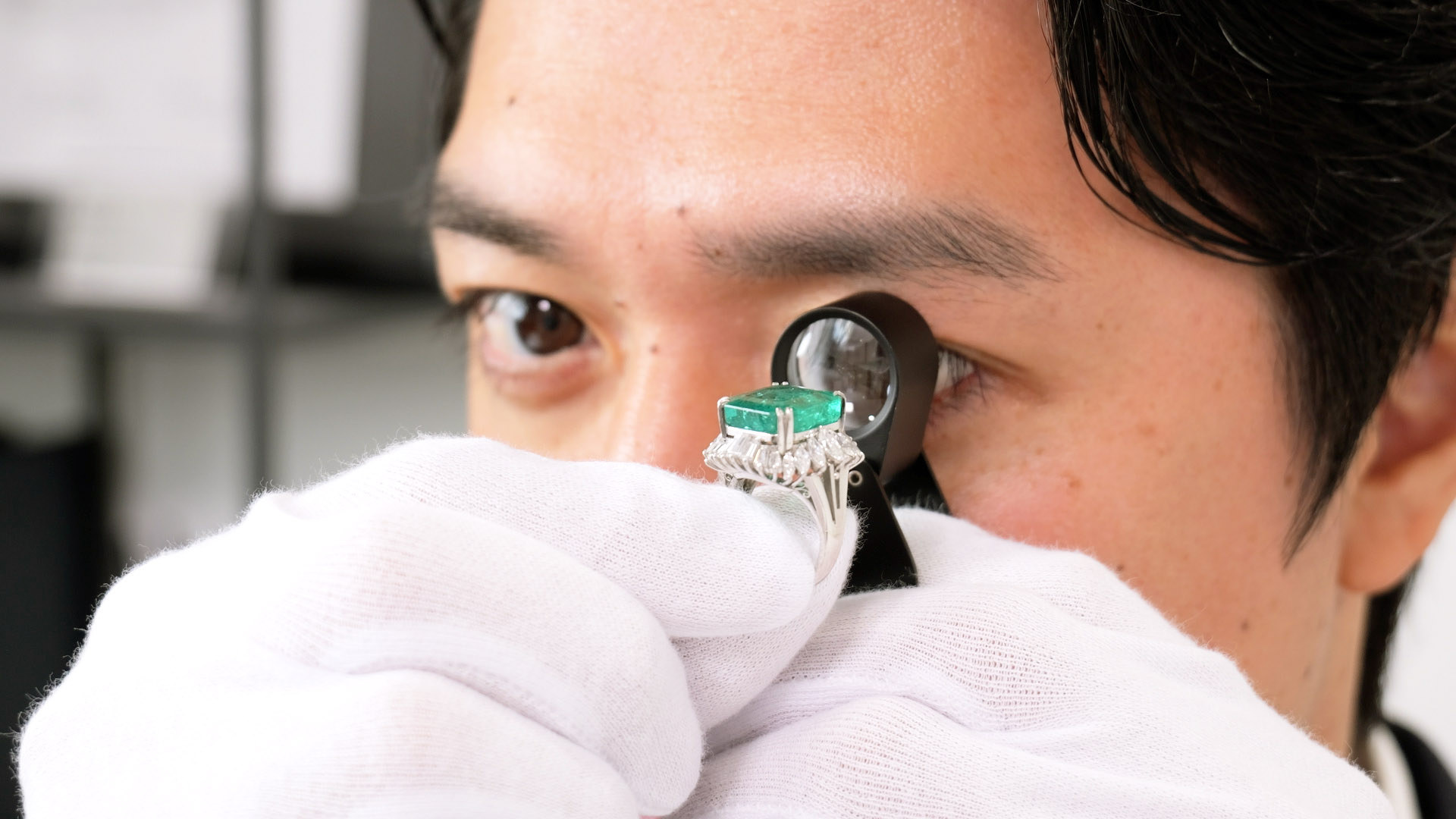 エメラルドを真剣に鑑定するGIA-GG資格を持つ鑑定士