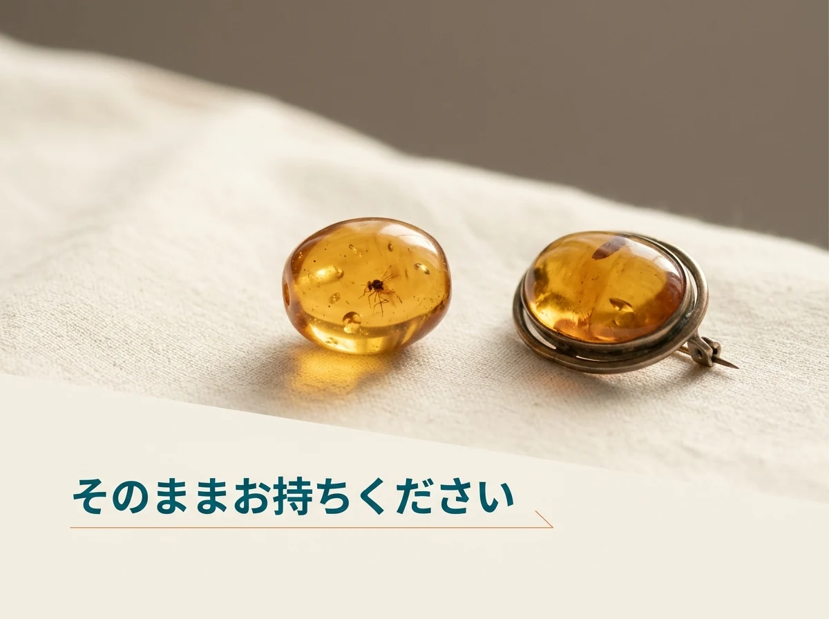 虫の入った琥珀のルースとブローチを布の上に並べた写真