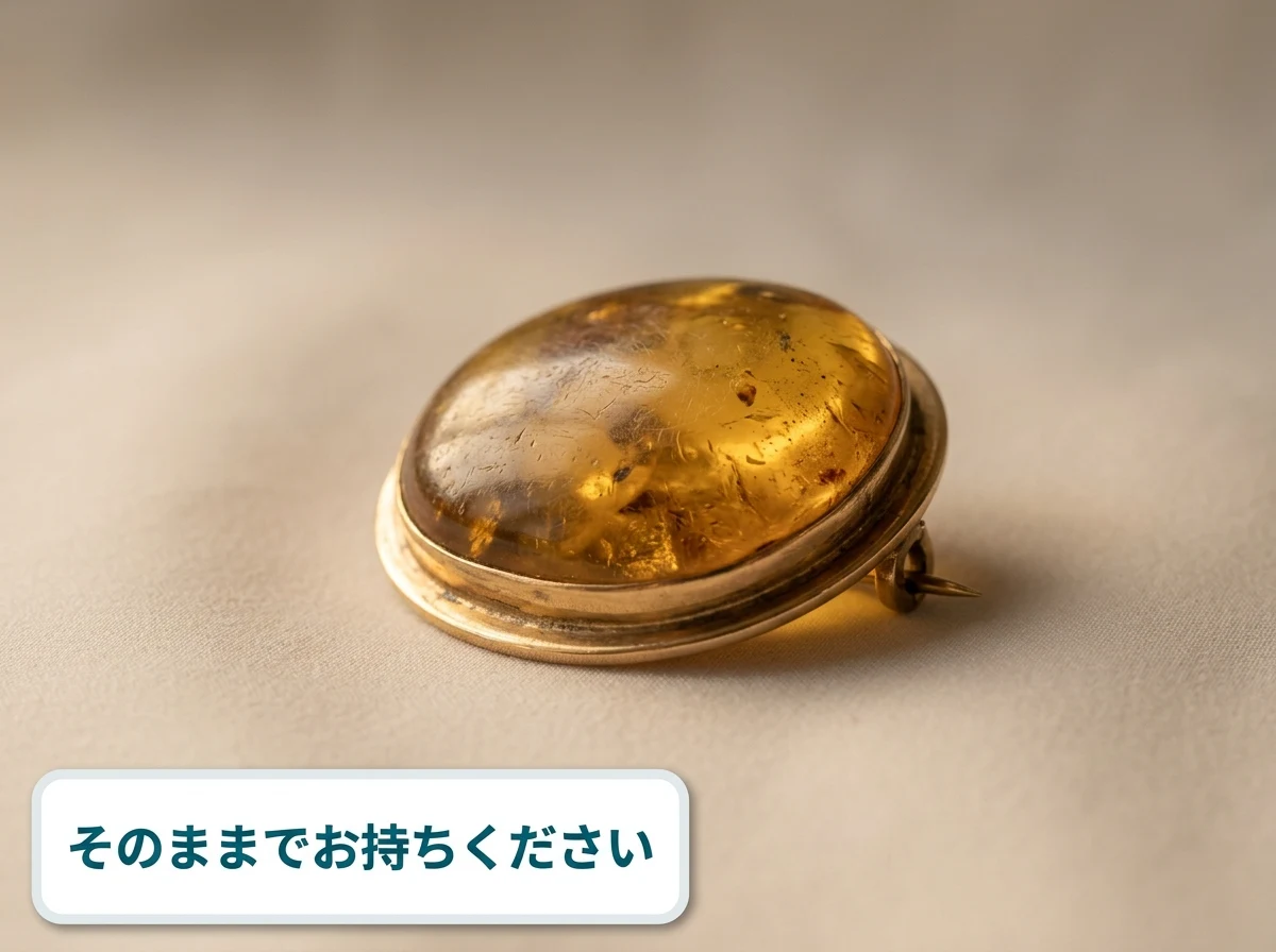 つやが落ちたままの琥珀のブローチをやわらかい布の上に置いた写真