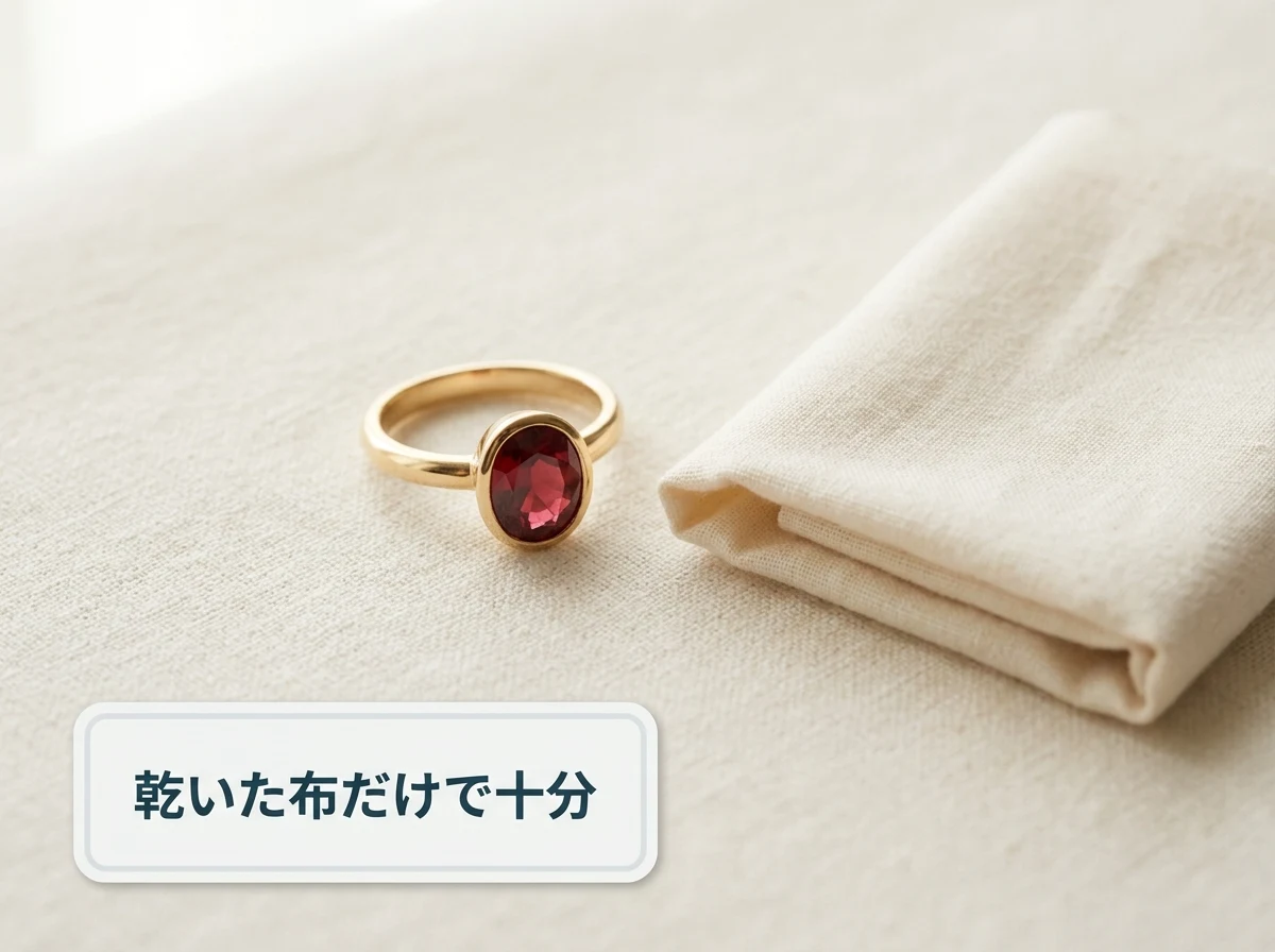 赤い石の指輪と折りたたんだ乾いた柔らかい布を布の上に並べた写真