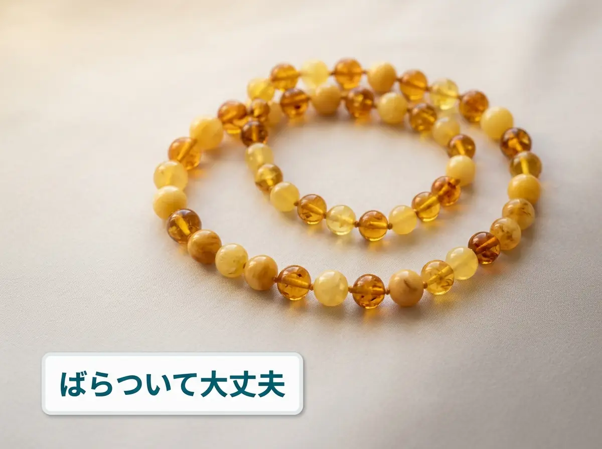 粒ごとに色の違う琥珀のネックレスを布の上に輪にして置いた写真